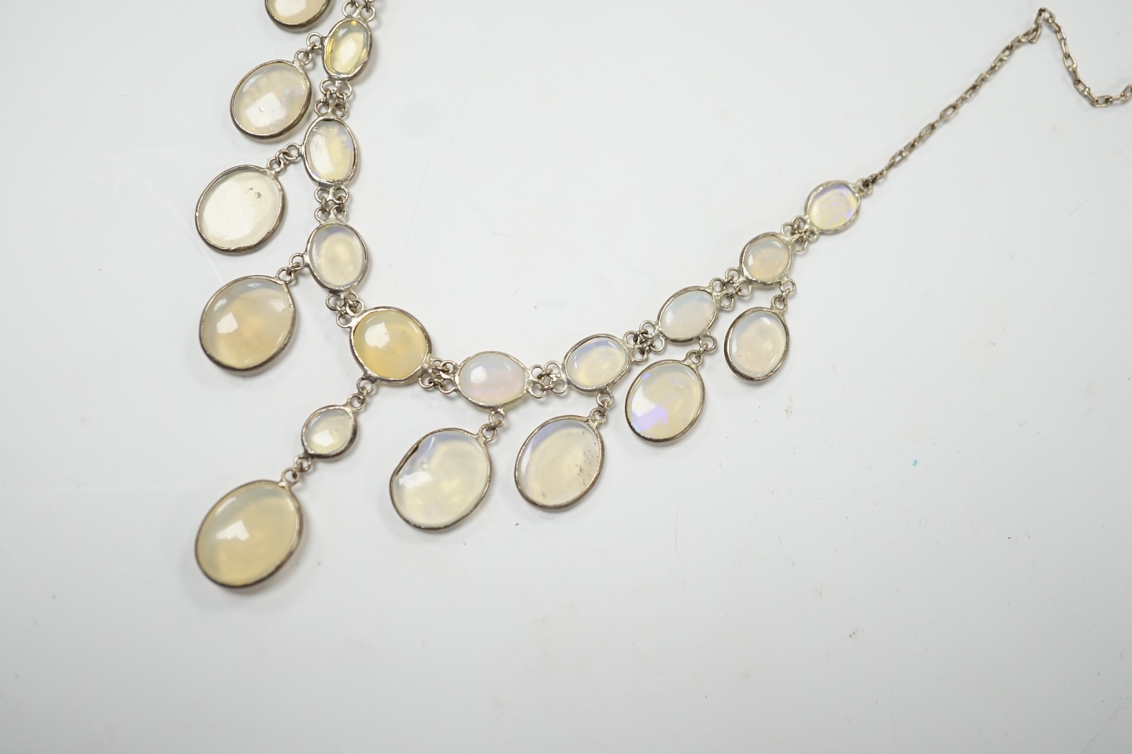 A white metal and graduated cabochon moonstone set drop necklace, 46cm. Fair condition